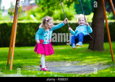 Petit garçon et fille sur une aire de jeux. Enfant jouant à l'extérieur en été. Les enfants jouent sur la cour de l'école. Happy kid en maternelle Banque D'Images