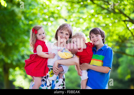 Grand-mère et ses petits-enfants profiter de pique-nique dans un parc. Grand-mère jouant avec des enfants dans une forêt ensoleillée d'automne Banque D'Images