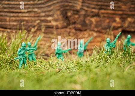 Petits soldats en plastique vert/armée de hommes en mission dans l'arrière jardin entouré de pelouse et fleurs Banque D'Images