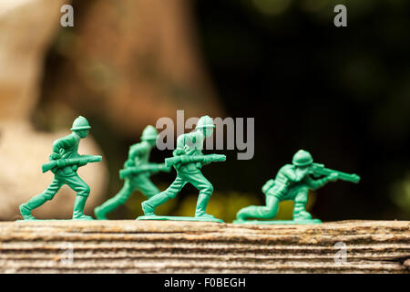 Petits soldats en plastique vert/armée de hommes en mission dans l'arrière jardin entouré de pelouse et fleurs Banque D'Images