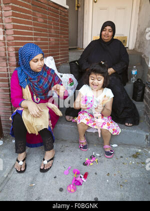 Bangladais girl playing on the stoop à foire de rue dans 'Little Bangladesh' dans la section de Kensington Brooklyn, New York. Banque D'Images