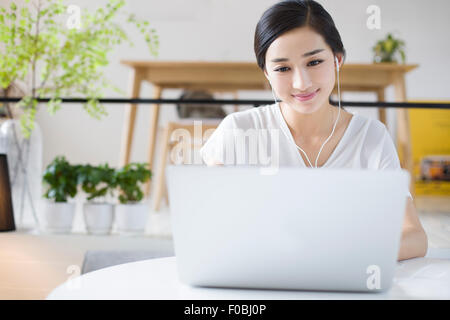 Happy young woman listening to music in coffee shop Banque D'Images