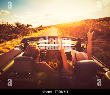 Jeune couple en voiture sur route de campagne et transformable au coucher du soleil Banque D'Images