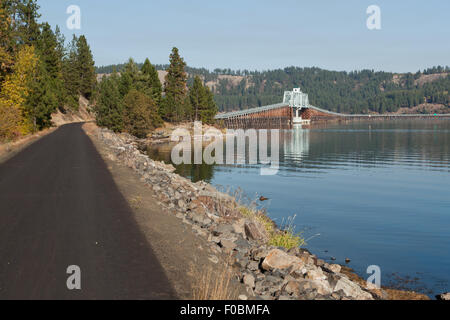 Un sentier pavé pour la marche ou le vélo à côté d'un lac qui mène sur un pont, de l'autre côté. Banque D'Images
