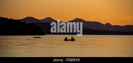 Canoë-kayak au coucher du soleil quand le soleil se couche derrière la crête de montagne Banque D'Images