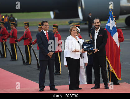 Comalapa, El Salvador. Août 11, 2015. Image fournie par la Présidence du Chili montre la présidente du Chili Michelle Bachelet (C) recevoir un présent de Nayib Bukele (R), maire de San Salvador, rejoint par le Chancelier salvadorienne Hugo Martinez (L) lors de son arrivée à l'Aéroport International El Salvador Comalapa, à 40 km au sud de San Salvador, capitale d'El Salvador, le 11 août 2015. Bachelet a commencé ce mardi une visite d'état d'El Salvador et du Mexique. Credit : Ximena Navarro/Présidence du Chili/Xinhua/Alamy Live News Banque D'Images