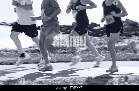 Groupe de coureurs en compétition dans la course sur route côtière. Blurred motion Banque D'Images