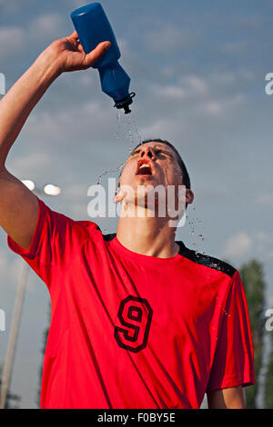 Jeune homme éjacule sur le terrain de soccer de l'eau face Banque D'Images