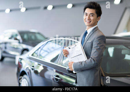 Confiant salesman standing avec de nouvelles voitures en showroom Banque D'Images