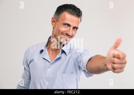 Portrait of a smiling woman showing thumb up sur fond gris Banque D'Images