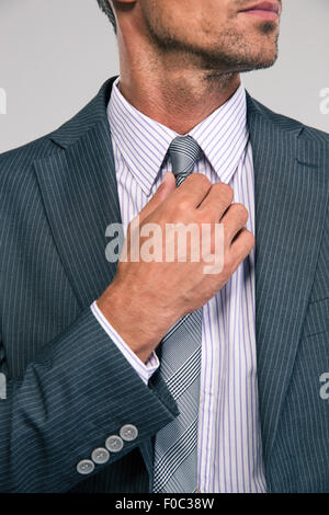 Closeup portrait of a businessman redressant sa cravate isolé sur fond blanc Banque D'Images