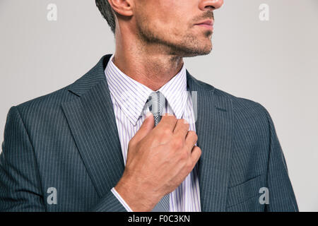 Closeup portrait of a businessman redressant sa cravate isolé sur fond blanc Banque D'Images