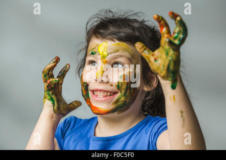 Smiling girl avec le visage et les mains peints sur fond gris Banque D'Images