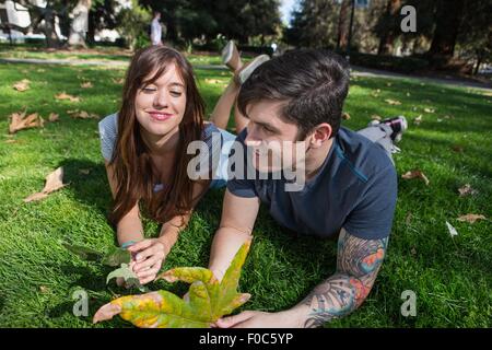 Young couple lying in park with autumn leaf Banque D'Images