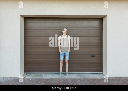 Portrait de jeune homme debout contre la porte de garage Banque D'Images