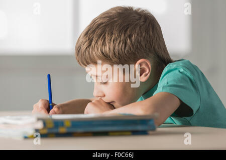 Vue latérale du garçon à faire des devoirs à la maison Banque D'Images