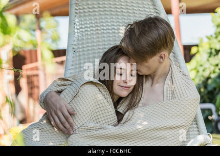 Jeune couple romantique enveloppée de couverture sur fauteuil suspendu à l'extérieur Banque D'Images