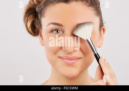 Young woman applying make-up Banque D'Images