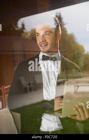 Tourné à travers la vitre de l'homme debout à la vue à la holding laptop Banque D'Images