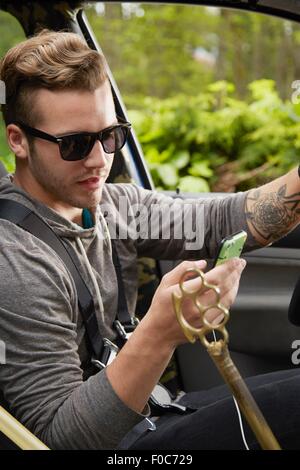 Portrait d'un homme portant des lunettes de conduite et l'utilisation de smart phone Banque D'Images