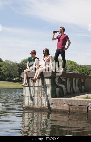 Multi-ethnic friends ayant la bière sur le mur de retenue par canal Banque D'Images