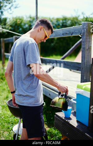 Young man pouring coffee pot de at park Banque D'Images