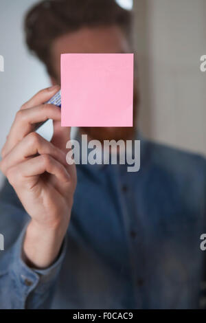 A noter bloqué sur mur de verre Banque D'Images