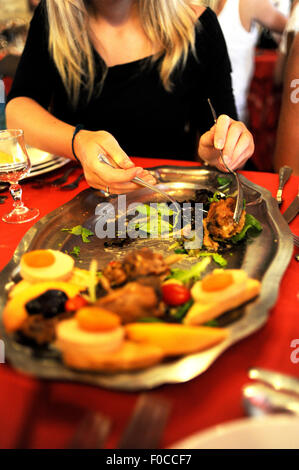 Teenage girl (15) au service d'une salade quercynoise traditionnelle de confit de canard foie gras de canard pate pruneaux et melon en France Banque D'Images