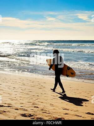 Man with surfboard marche sur la plage de l'océan. Sagres, Algarve, Portugal Banque D'Images