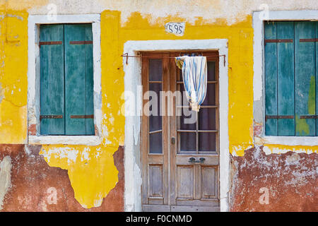 En décomposition de déroulage avant d'une maison aux volets peints de couleurs vives Burano Lagune de Venise Vénétie Italie Europe Banque D'Images