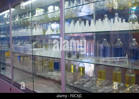 Bouteilles de produits chimiques dans un boîtier en verre dans un laboratoire Banque D'Images