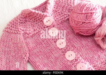Veste en laine Bébé rose tricoté avec de grosses touches, avec boule de fils sur le côté Banque D'Images