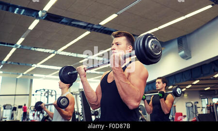 Groupe d'hommes flexing muscles avec barbell in gym Banque D'Images