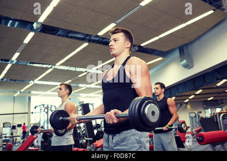 Groupe d'hommes flexing muscles avec barbell in gym Banque D'Images