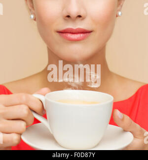 Femme en robe rouge avec tasse de café Banque D'Images