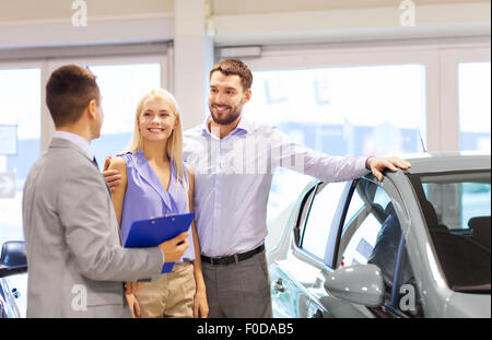 Couple heureux avec concessionnaire automobile à auto show ou salon Banque D'Images