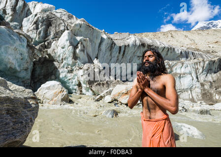 Un Sadhu, saint homme, est debout et priant sur un rocher à Gaumukh, la principale source de la sainte gange, Gangotri, Uttarakhand Banque D'Images