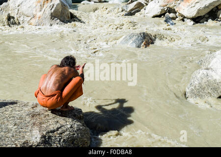 Un Sadhu, saint homme, est assis sur un rocher et en priant à Gaumukh, la principale source de la sainte gange, Gangotri, Uttarakhand Banque D'Images