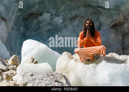 Un Sadhu, saint homme, est assis et priant dans lotus pose, le Padmasana, sur un bloc de glace à Gaumukh, la principale source de la sainte Banque D'Images