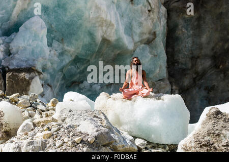 Un Sadhu, saint homme, est assis et méditant dans lotus pose, le Padmasana, sur un bloc de glace à Gaumukh, la principale source de la sainte Banque D'Images