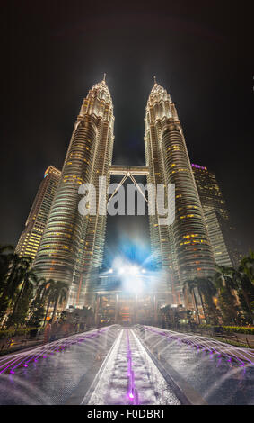 Fontaine en face de la tour Petronas illuminée la nuit, Kuala Lumpur, Malaisie Banque D'Images