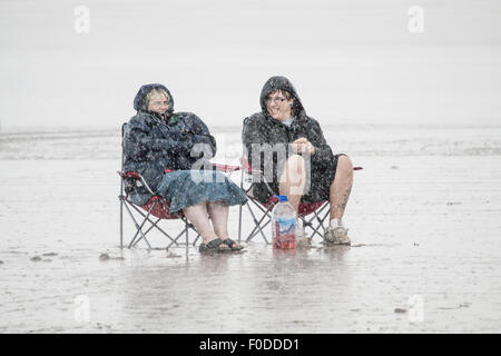 Deux personnes assis sur une plage dans une tempête de pluie Banque D'Images