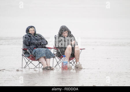 Deux personnes assis sur une plage dans une tempête de pluie Banque D'Images