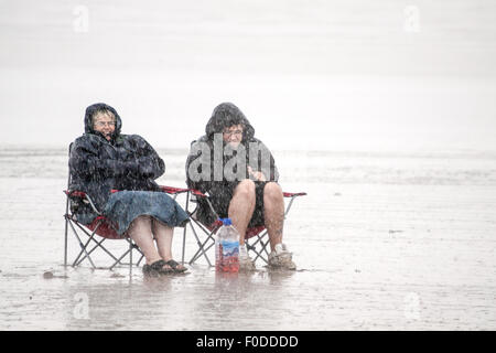 Deux personnes assis sur une plage dans une tempête de pluie Banque D'Images