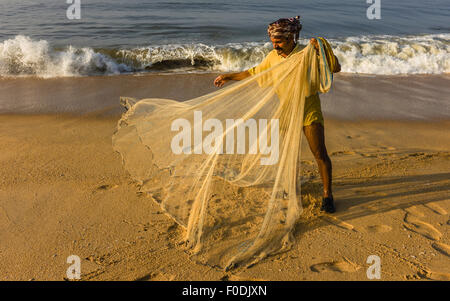 Un pêcheur s'apprête à enregistrer son petit filet de la plage de sable dans la mer d'Oman. Banque D'Images
