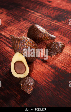 De délicieux fruits salak sur fond texturé en bois brun. Fruits tropicaux, rustique. Banque D'Images