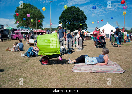 Les familles se réunissent autour de stands de nourriture et de tentes de l'événement dans le soleil d'été au Port Eliot Cornwall Festival Banque D'Images