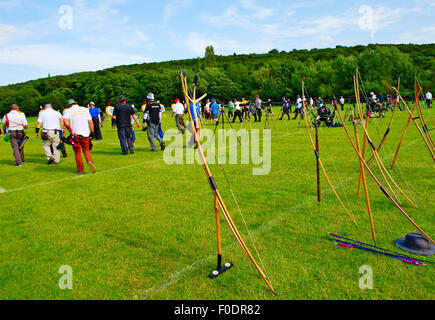 La compétition de tir à l'arc, rangée d'arcs traditionnels alignés derrière la ligne de tir avec les archers à pied de flèche pour récupérer des cibles Banque D'Images