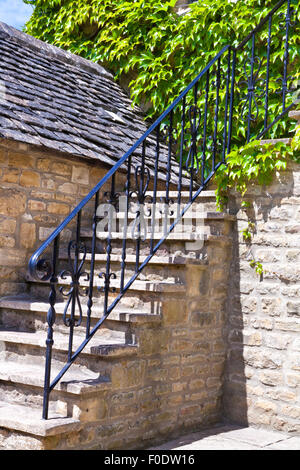 Escalier en pierre dans un vieux chalet, avec garde-corps en métal et le mur couvert de plantes raisin vigne verte Banque D'Images