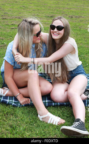 Deux adolescentes assis sur l'herbe en été, laughing Banque D'Images